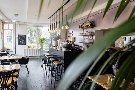 Il bancone di un bar con gli sgabelli e la macchina del caffè