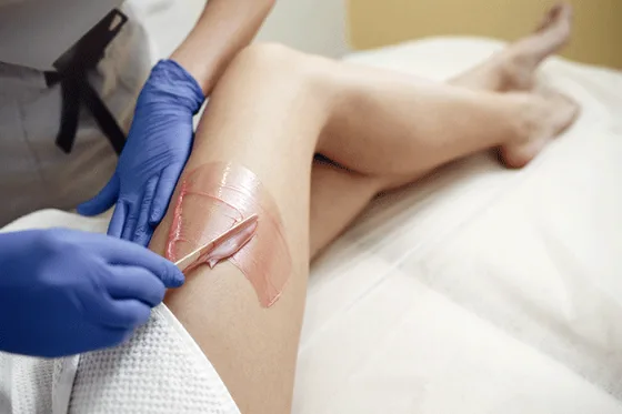 Un'estetista che applica la cera con i guanti