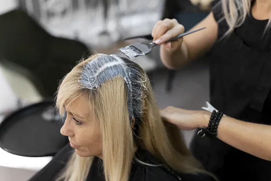 Una parrucchiera che applica il colore a una cliente