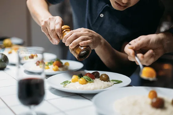 Un cuoco che completa un piatto in cucina