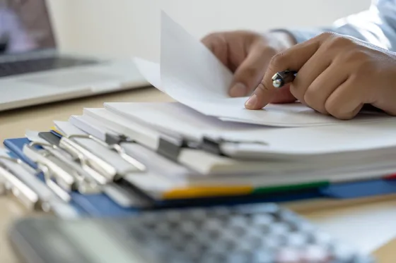 Una scrivania con documenti, calcolatrice e computer